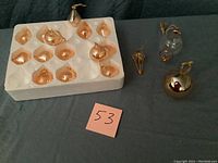 Photo showing 14 amber-colored Princess House glass ornaments in styrofoam tray and 2 additional ornaments outside the tray