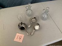 Photo showing 2 crystal spoon rests, 3 stainless steel measuring cups, and 2 crystal oil dispensers on table.