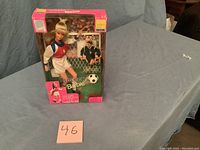 Full view of Barbie doll in original box, showing soccer themed packaging and doll dressed in soccer outfit.
