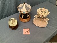 Three music boxes including two carousel horses and one snow globe horse on a table