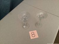 Two clear crystal chandelier candle holders on a table, viewed from above showing the top cups and stems.