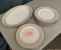 Eight round dinner plates stacked alongside one oval serving tray on a folding table