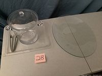 Ice bucket with lid and side handles on rectangular serving tray, with ice tongs, next to large oval serving tray.