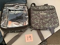 Two Princess House insulated cook and carry totes side-by-side, showing front exterior with vine pattern and front zipped pockets.