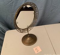 Front view of the Princess House Gloria Decor round decorative mirror on stand showing etched leaf pattern on glass perimeter and round weighted metallic base.
