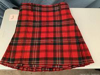 Red Scott Clan traditional tartan kilt laid out flat showing pleated design and pattern.