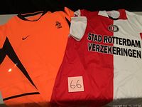 Photo showing two soccer jerseys: bright orange Dutch National Team jersey with black accents and Nike logo, and white/red half split Feyenoord Rotterdam jersey with sponsor text and club badge.
