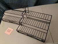 Two black metal wire stepped organizer shelves shown from angled top view on a white surface with a '25' note.