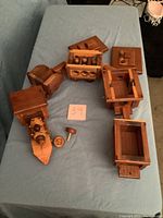 Photo showing the wooden engine and 4 connected wooden cars laid out on a fabric surface. The engine features a broken axle.