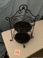 Front angled view of the two tier metal fruit basket with ornate scrollwork and leaf accents.