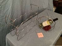 Silver metal wire 12-slot wine rack and silver wire decorative wine caddy with a bottle and grapes on grey cloth
