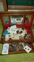 Overview photo of the jewelry pieces inside a wooden jewelry box with mirrored compartments showing mixed costume jewelry items.