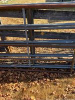 Galvanized tubular panels leaning against wooden fence