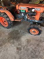 Side view of entire tractor showing flat front tire, engine block, and rear tire