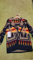 Front view of Pendleton blanket coat by Cry Wolfe showing geometric Navajo pattern in navy, tan, red, orange and yellow