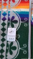 Close-up of multicolor striped pattern and green medallion motif with lot tag