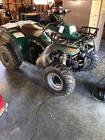 Left side view of green Polaris Xplorer ATV showing body panels, tires and seat.