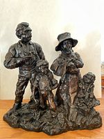 Front view of bronze sculpture depicting a man, a woman with a baby, and two children on a textured base.