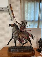 Full front view of the bronze sculpture on wooden base