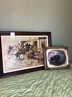 Two framed art pieces side by side on green bedding