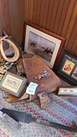 Framed western artwork, leather chaps, small rug and western decorative items laid out