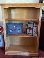 Front view of oak bookshelf holding two pillows