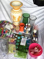 Photo showing decorative ceramic vase, two glass vases, orange vase, multiple craft supplies including acrylic paint, bracelet making kit.