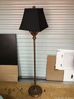 Full view of brass-colored floor lamp with black shade showing overall structure and condition.