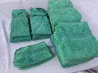 Full view of all towels grouped in stacks by size, showing the green color and fabric texture.