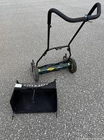 Manual reel lawn mower 18-inch cut width with foam grip handles and large wheels placed on pavement