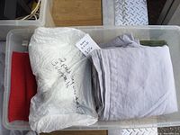 Gray and white linens folded in bin, gray set tagged as new from Lands End