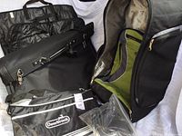 Photo showing black suit cases for suits, green and black upright suitcase, and black lunch cooler bag with Deerbrook branding.