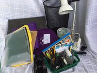 Photo showing foot rest, small trash can, lamp, office supplies and cords