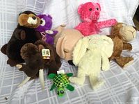 Photo of all 8 stuffed animal toys arranged on a white surface, displaying various plush animals from beaver to turtle.
