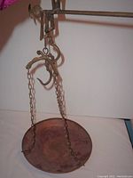 View of copper pan attached to hanging brass hardware with chains and hooks for weighing.