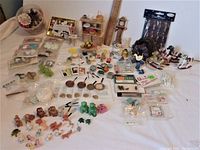 Full display of assorted vintage miniatures, figurines, and craft items laid out on a white surface.