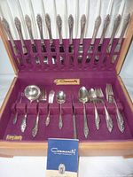 Overall view of silverware set in purple velvet-lined Guti-Tarnish container, showing knives standing upright and other utensils laid in slots.