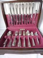Full set of silver plated flatware items arranged inside lined flatware canteen.