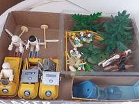 Photo showing yellow snowmobile style vehicles with figurines, miniature trees, floral accessories, and a green dinosaur figure.