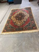 Full view of the area rug showing its medallion design and overall color palette with red, beige, green, and black tones.