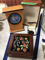 Wooden table clock, open wooden box with label showing dimensions, jewelry box with pendant and earrings, and closed wooden box with hand-painted lid.