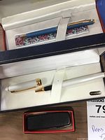 Eaton rollerball pen in case, Sheaffer pen in case, black pocket cutter in box below