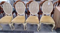 Front view of all four chairs in a row showing cane backs and velvet seats