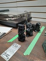 Three aboriginal and other black stone carvings arranged on a table with turntable in background