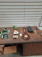 Photo of all items displayed on a wooden table including three stone animal figures, the leather barometer, and the carved wooden mask