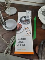 Front view of the Anova Nano original packaging with 'Cook Like A Pro' tagline and image of plated food and mobile app display.