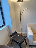 Photo of solid wood bench with dark finish and scratches beside metal floor lamp in corner
