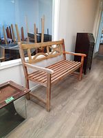 Front and side views of the wooden exterior bench showing the slatted seat, circular decorative backrest design, and armrests with scratches and wear.