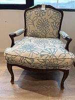 Front view of cushioned arm chair showing floral upholstery and wood frame