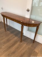 Side view of wood console table showing curved front edge and turned legs